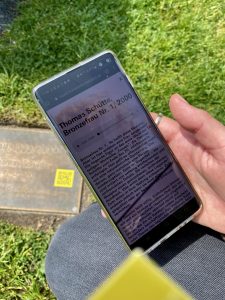 Ein Tablet mit Text zu einer Skulptur, auf dem Boden ist ein gelber QR-Code erkennbar.