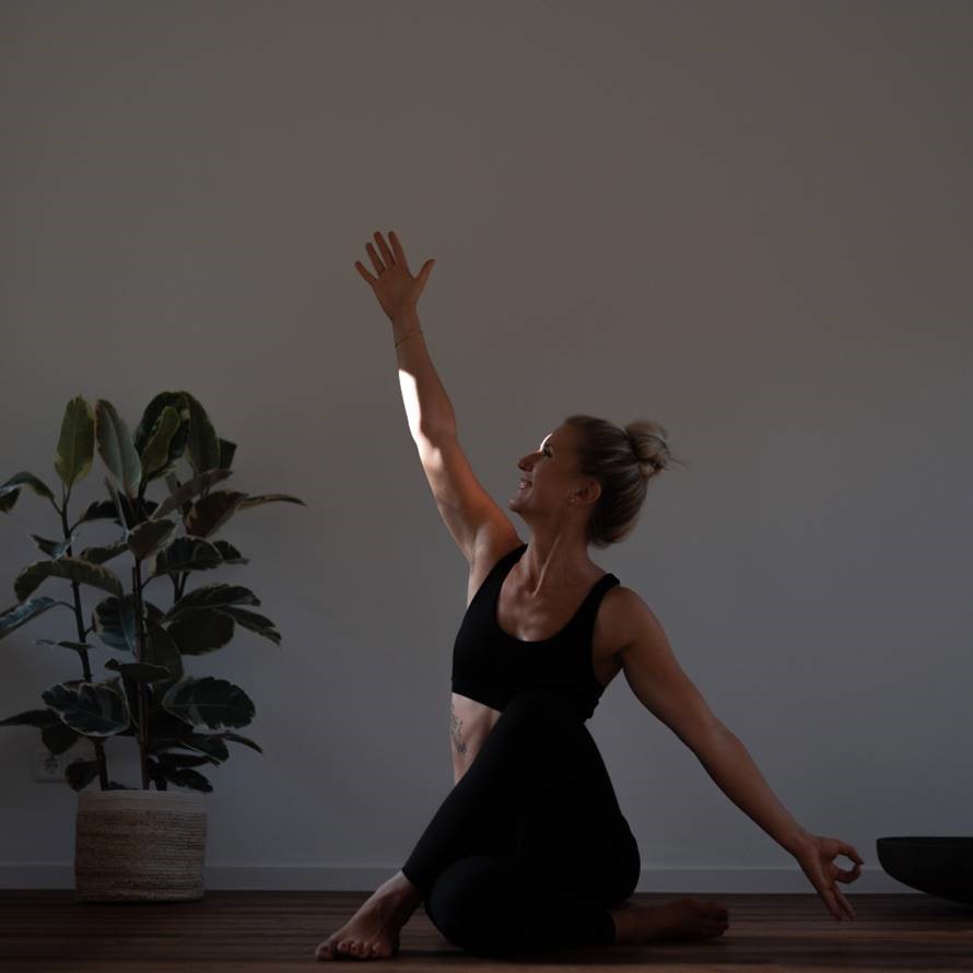 Woman in sitting yoga pose with arms outstretched