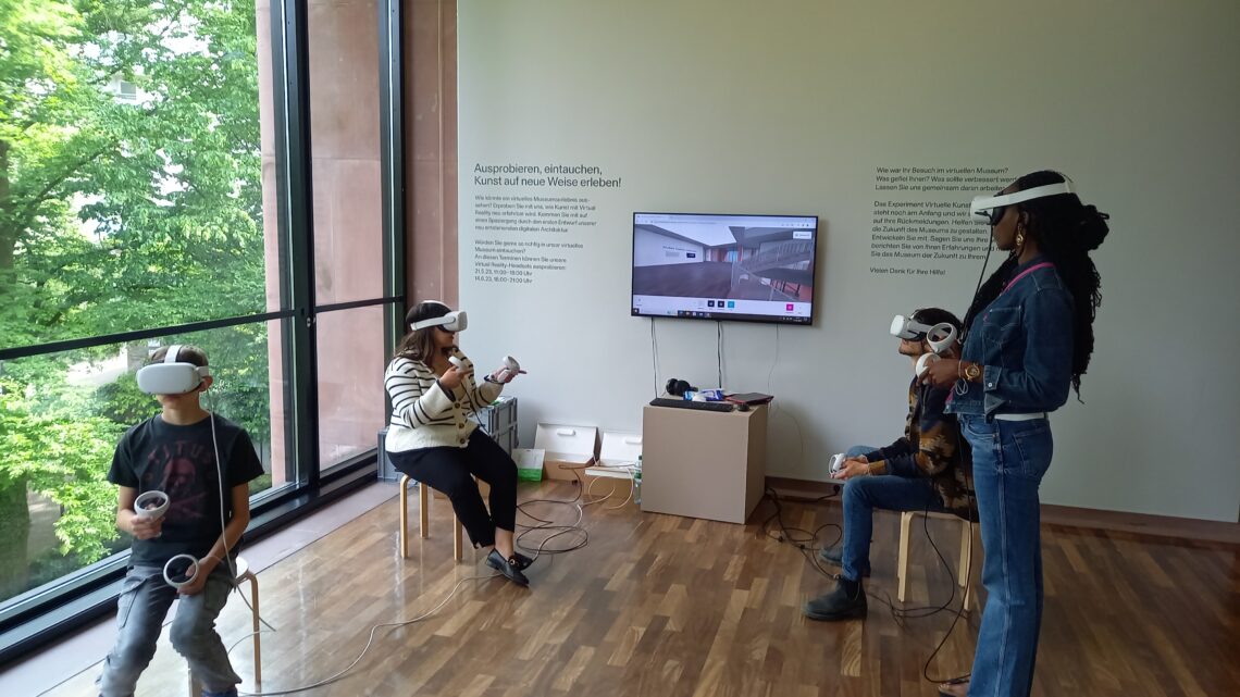 Vier Personen verschiedenen Alters, stehend und auf Hockern sitzend, tragen Virtual Reality Headsets. An der Wand hinter ihnen sieht man, welche Computeranwendung sie gerade testen.