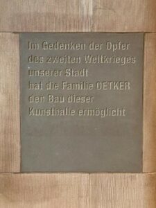 Foto einer in die Wand eingleassenen Gedenktafel. Aufschrift: Im Gedenken der Opfern des zweiten Weltkrieges unserer Stadt, hat die Familie Oetker den Bau dieser Kunsthalle ermöglicht.
