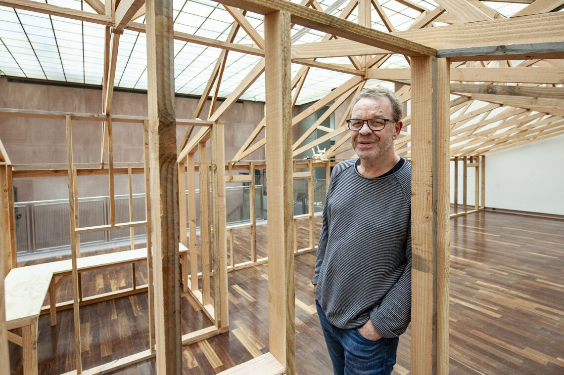 Stefan Brams steht in Oscar Tuazons Werk "Building", eine Holzkonstruktion in Form eines Langhauses