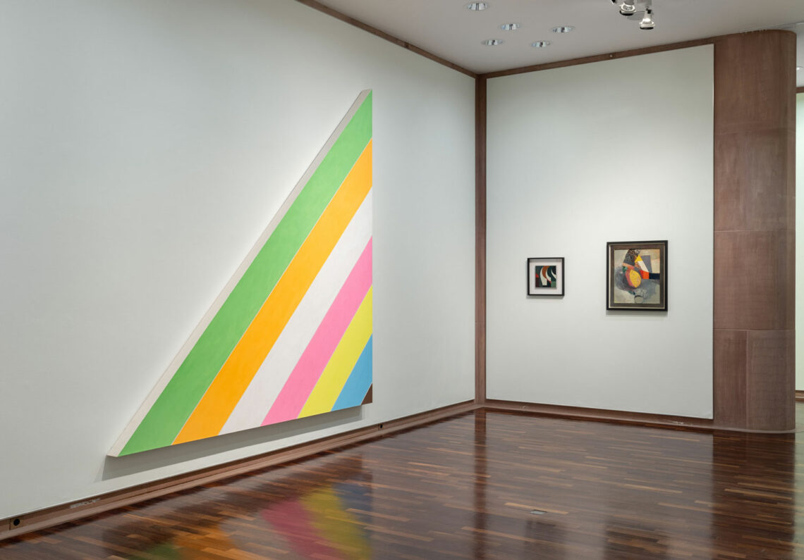 Zwei Wände über Eck in der Kunsthalle: Links ein großes rechtwinkliges Dreieck, dessen Grundlinie von links unten nach rechts oben weist. Parallel dazu laufen breite Linien in freundlichen Farben.