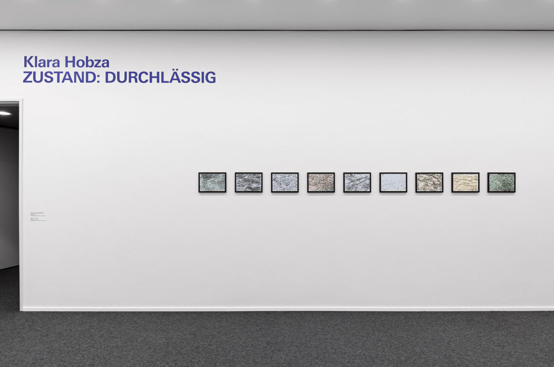 Eine weiße Wand in der Kunsthalle, davor Teppichboden. Auf der Wand etwa in mittlerer Höhe 9 kleinformatige Tuschezeichnungen.